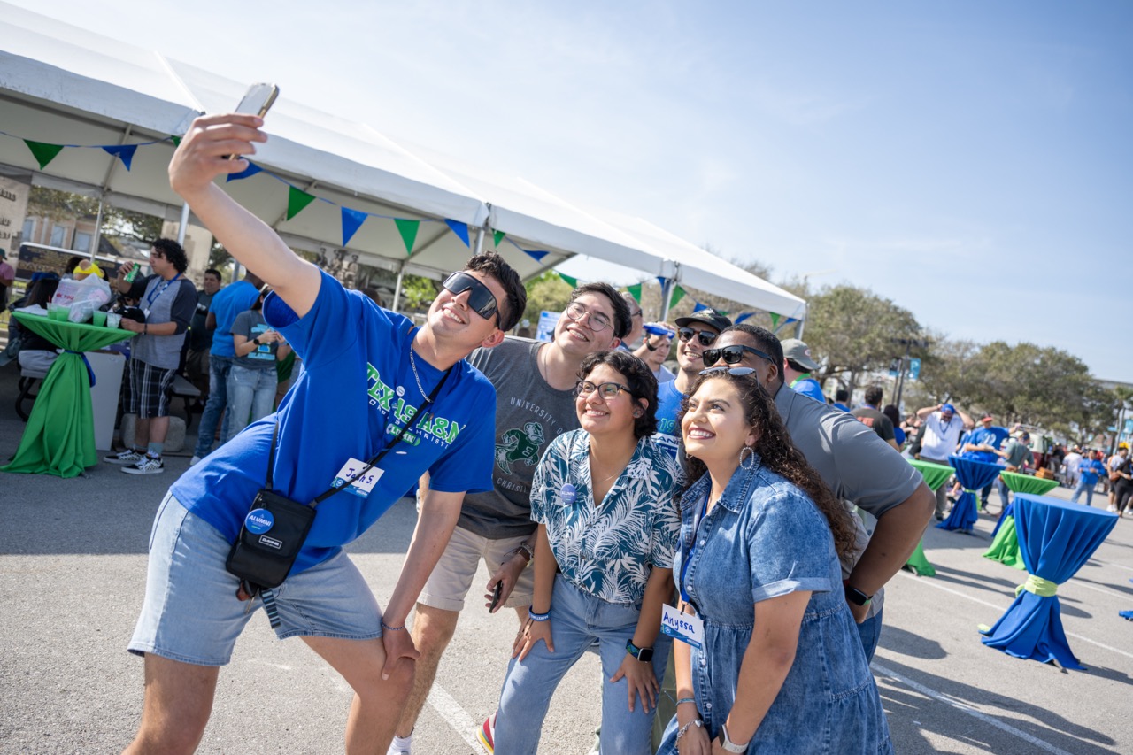 Young Islander Alumni at the Homecoming Block Party taking a group selfie.
